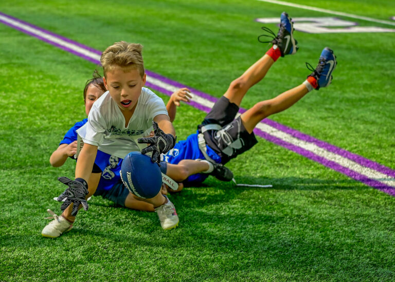 Young football players sliding on the grass