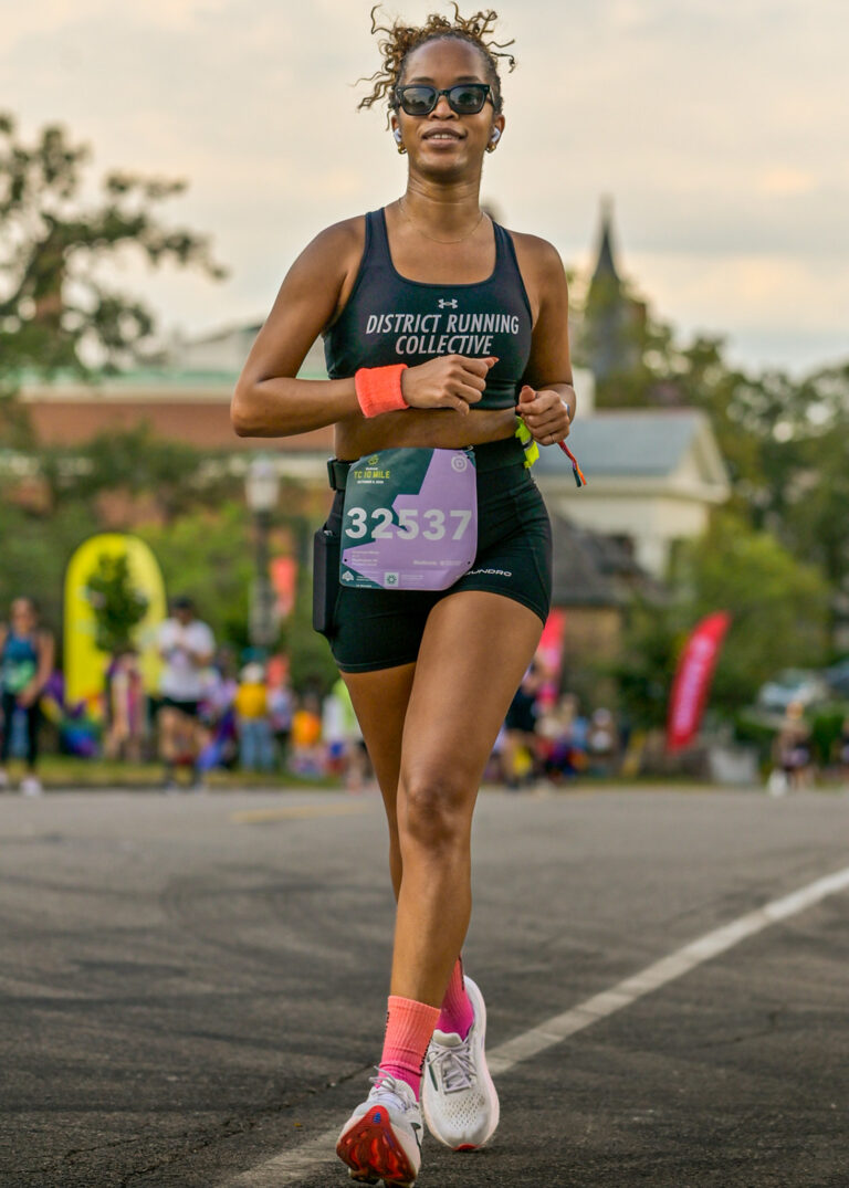 Runner in dark athletic wear and a race bib running on the road