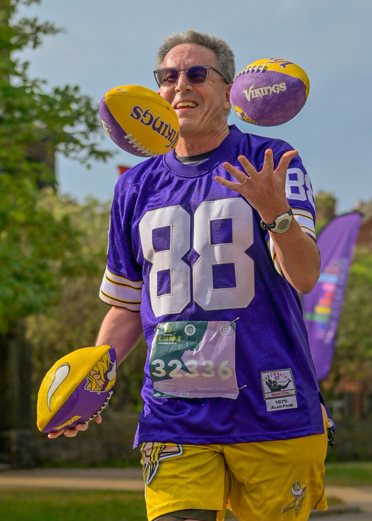 Runner juggling Minnesota Vikings footballs during a race, running photography Minneapolis