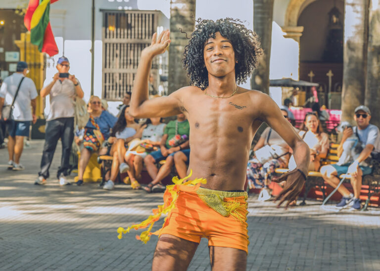 Dancer in an orange costume performing in front of a festival crowd