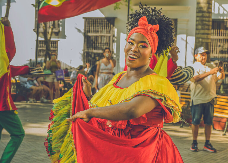 Dancer with a red head wrap twirling in a yellow and red dress at a street festival