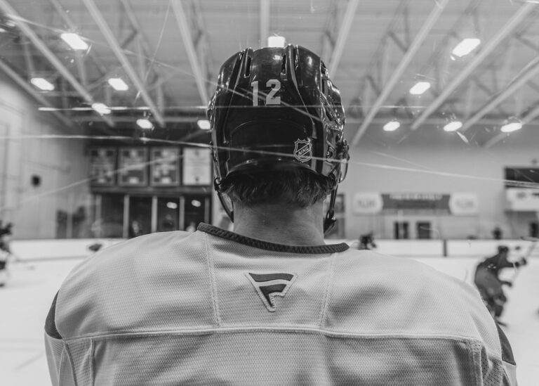Hockey player wearing a helmet seen from behind in black and white
