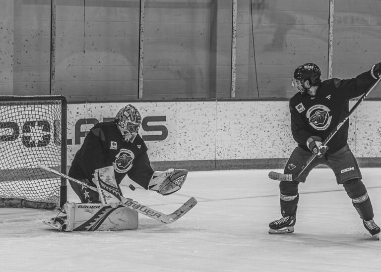 Hockey goalie dropping to make a save in front of the net
