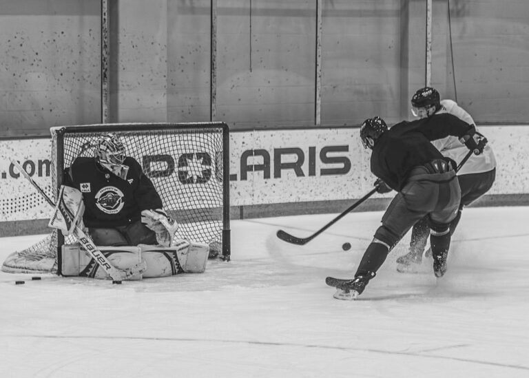 Hockey goalie making a save during a practice drill in black and white
