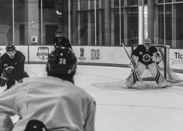 Hockey goalie and a skater in front of the net in black and white