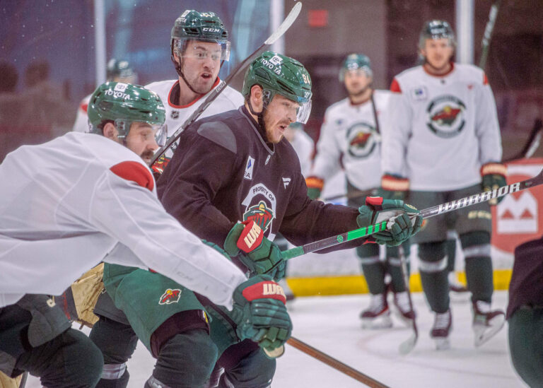 Hockey players in green and white jerseys battling for the puck