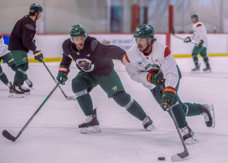 Two hockey players skating for the puck in a practice drill