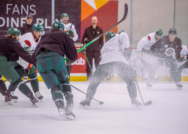 Hockey players battling for the puck along the boards