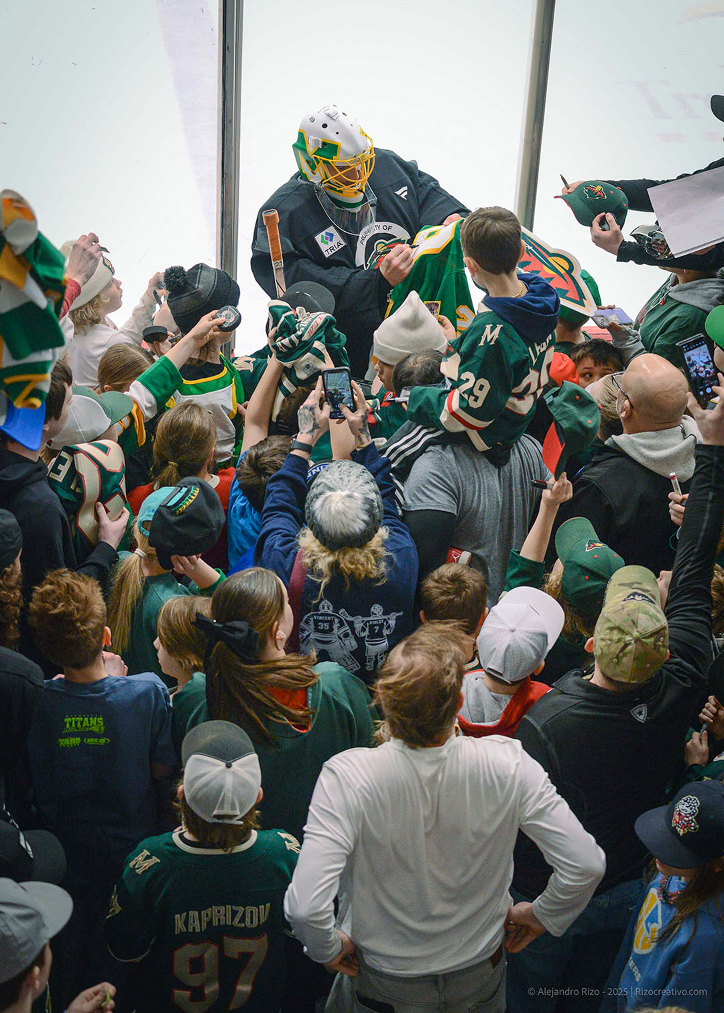 Fans in green hockey jerseys crowding the rink boards