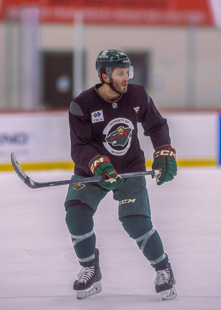 Hockey player in a practice jersey holding a stick on the ice