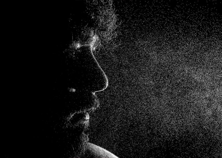 Profile portrait of a man lit against black with fine grain