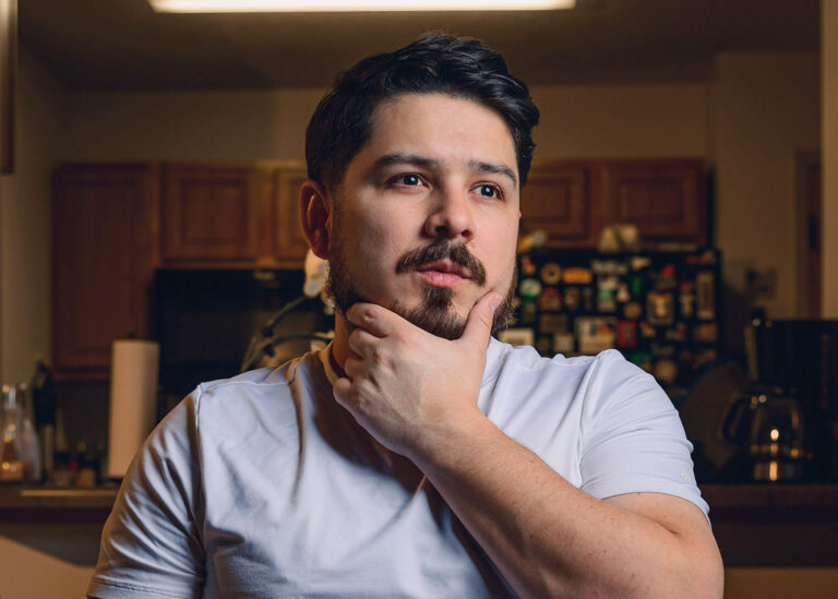 Portrait of a man resting his hand on his chin in a relaxed indoor setting