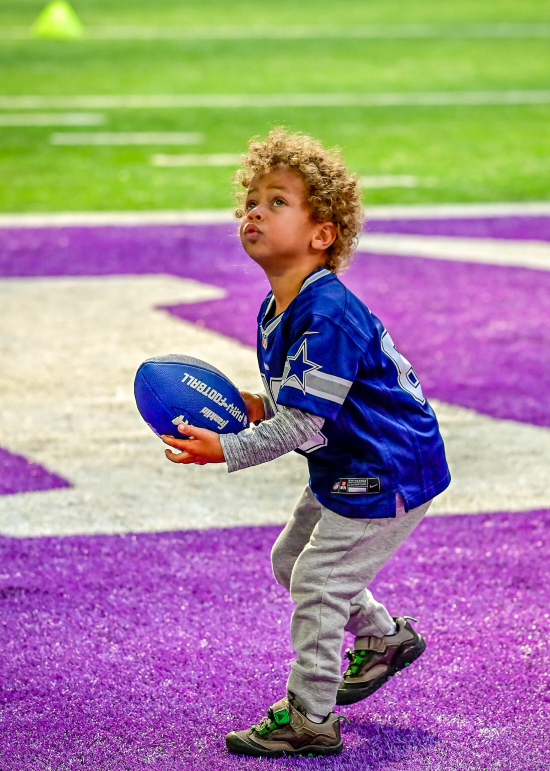 Young football player holding the ball in a stadium, sport photography