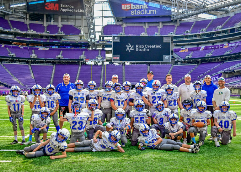 Youth football team posing together on the field inside a stadium