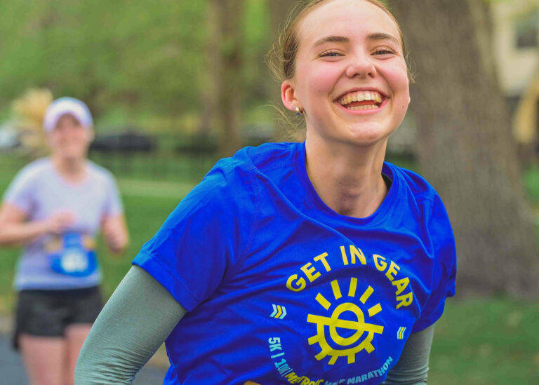 Smiling runner in a blue Get in Gear shirt during a race