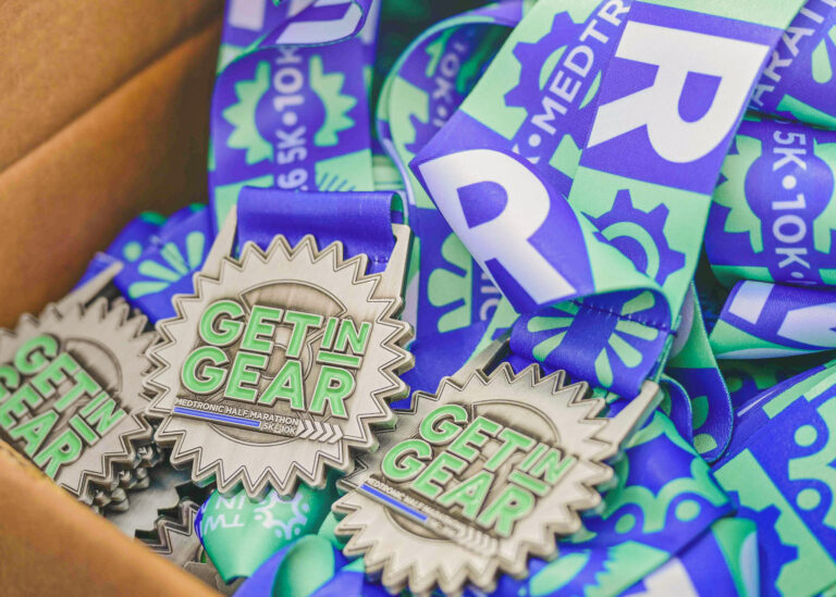 Pile of Get in Gear finisher medals on blue ribbons in a box