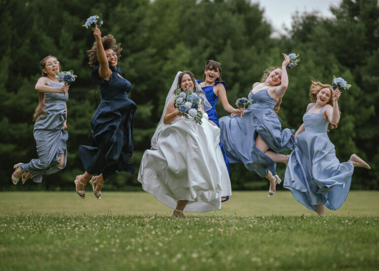 Bride and bridesmaids jumping in the air on a green lawn