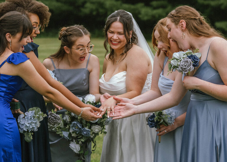 Bride and bridesmaids in blue dresses leaning in together holding bouquets