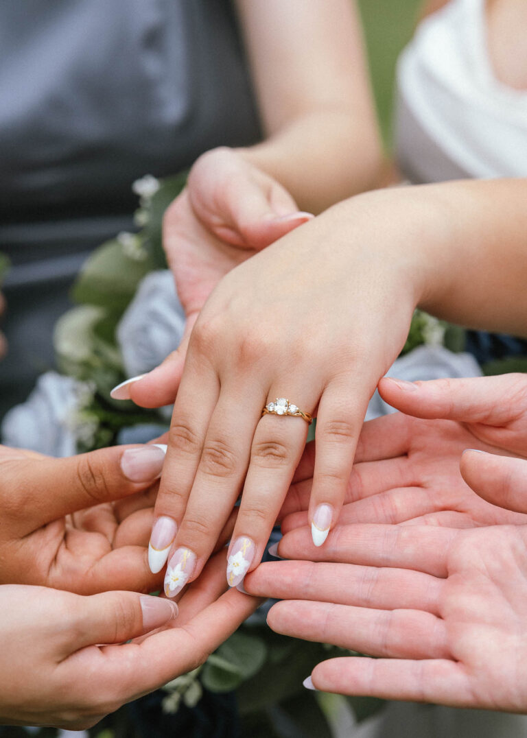 Close-up of the couple's hands with wedding rings beside a bridal bouquet