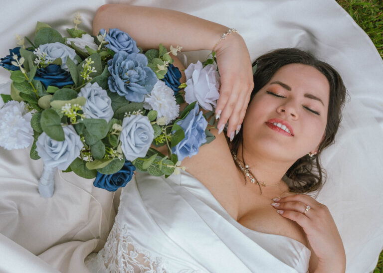 Bride lying down and smiling with a blue and white bouquet