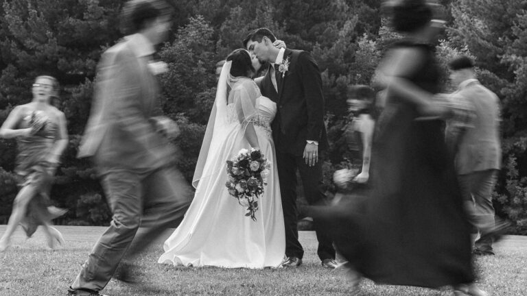 Bride in white walking with the wedding party in motion, in black and white