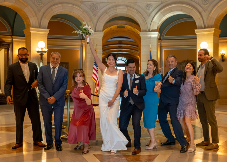 Wedding group celebrating together in a grand arched hall