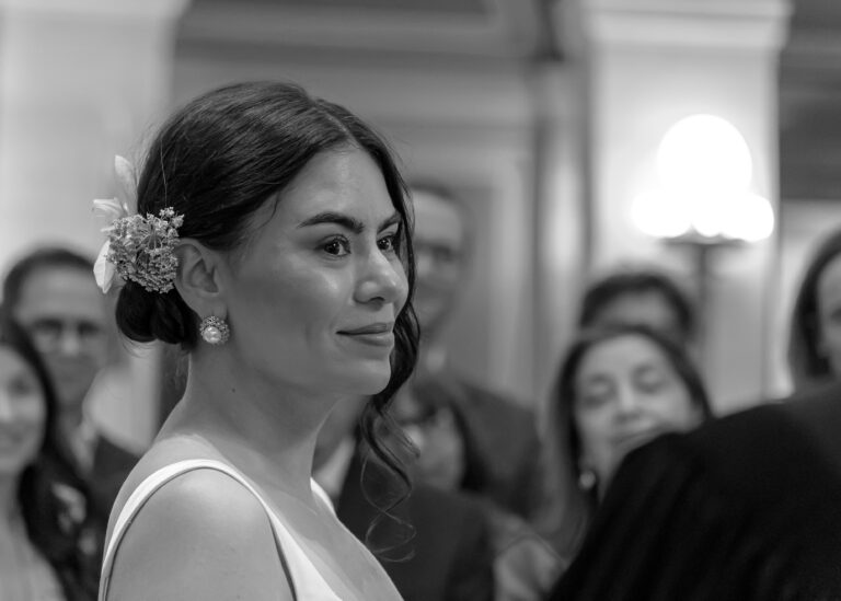 Bride with flowers in her hair smiling during the ceremony, in black and white