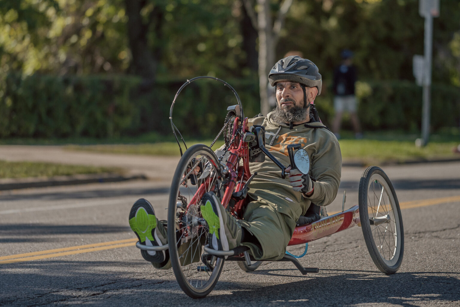 Hand cyclist in a helmet pedaling a red handcycle along the course during the Twin Cities Marathon